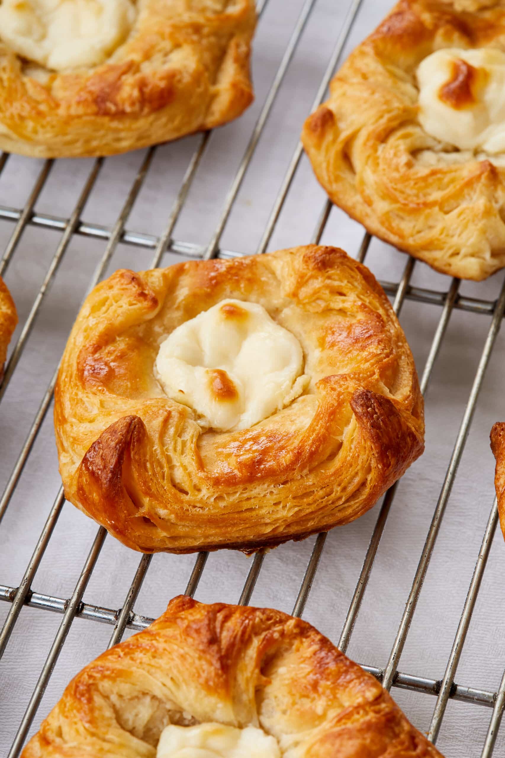 Golden, flaky Cheese Danish are cooling on a wire rack.