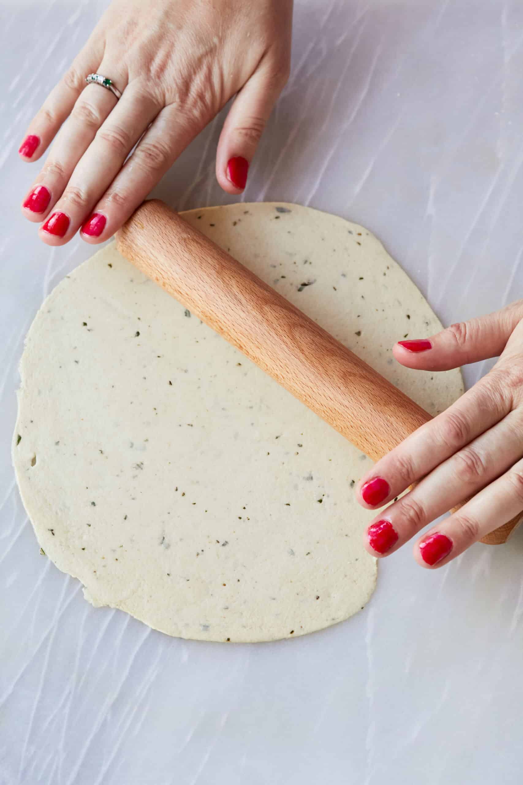 Step-by-step instructions on how to make Carta di Musica: Brush a work surface with a touch of oil and, working with one ball of dough at a time, roll the dough into a circle as thin as possible, about 8 inches (20cm).