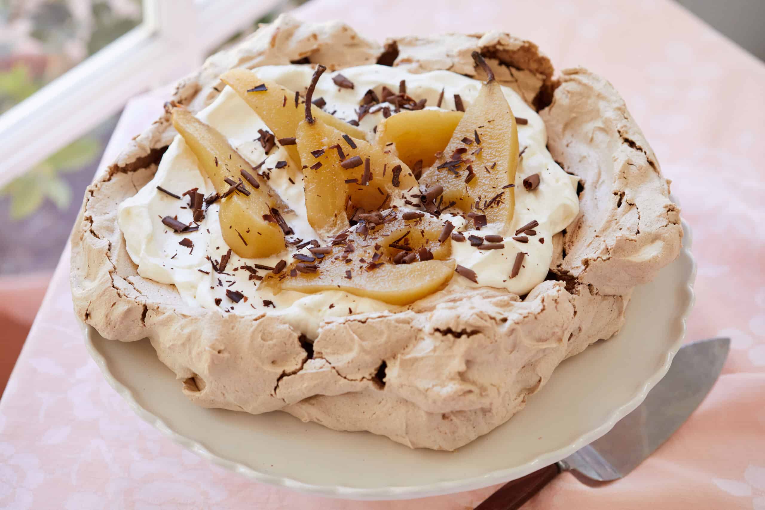 Crispy Baked Chocolate Meringue is topped with mascarpone whipped cream, then poached pears and chocolate shaves.