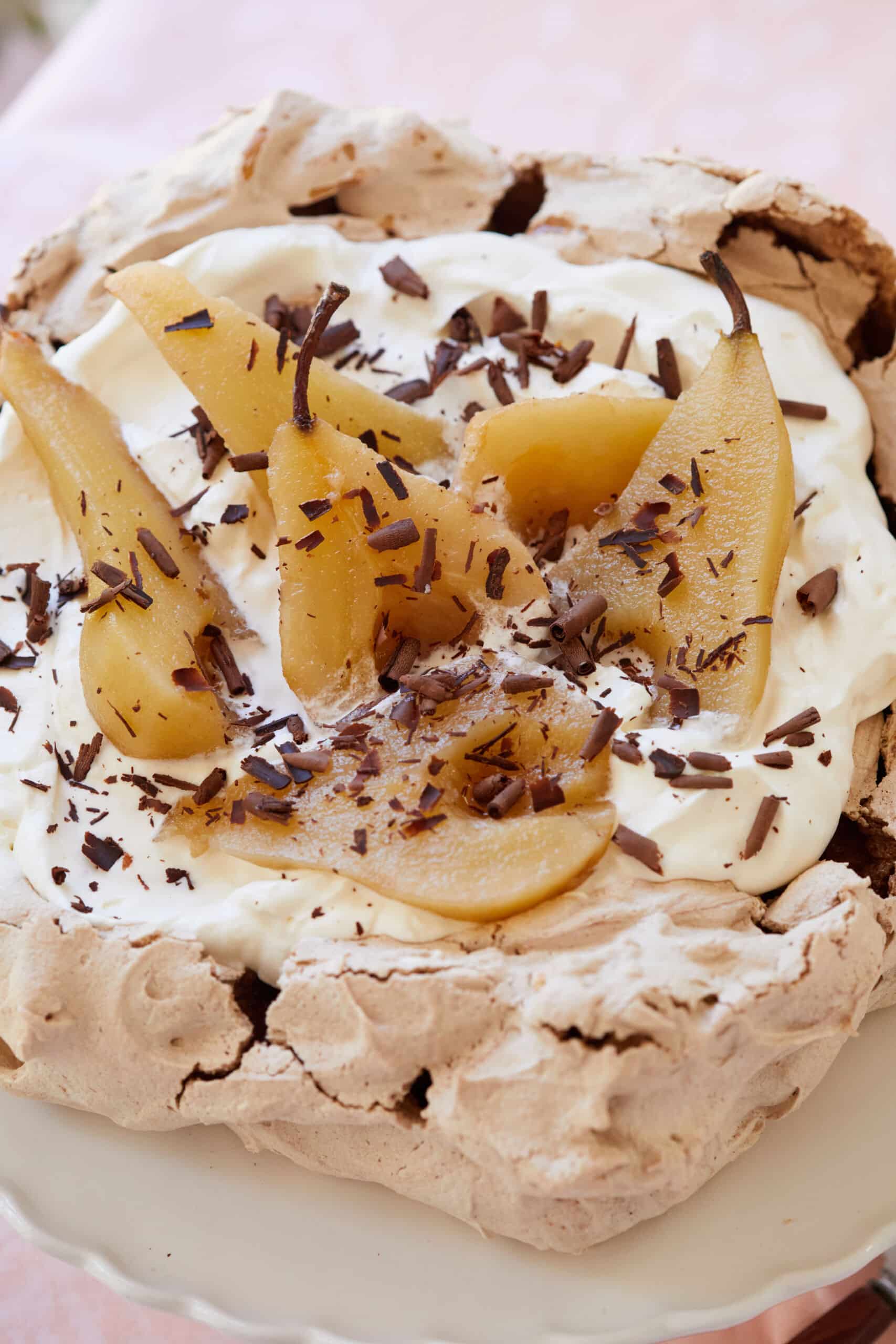 Crispy Baked Chocolate Meringue is topped with mascarpone whipped cream, then poached pears and chocolate shaves.