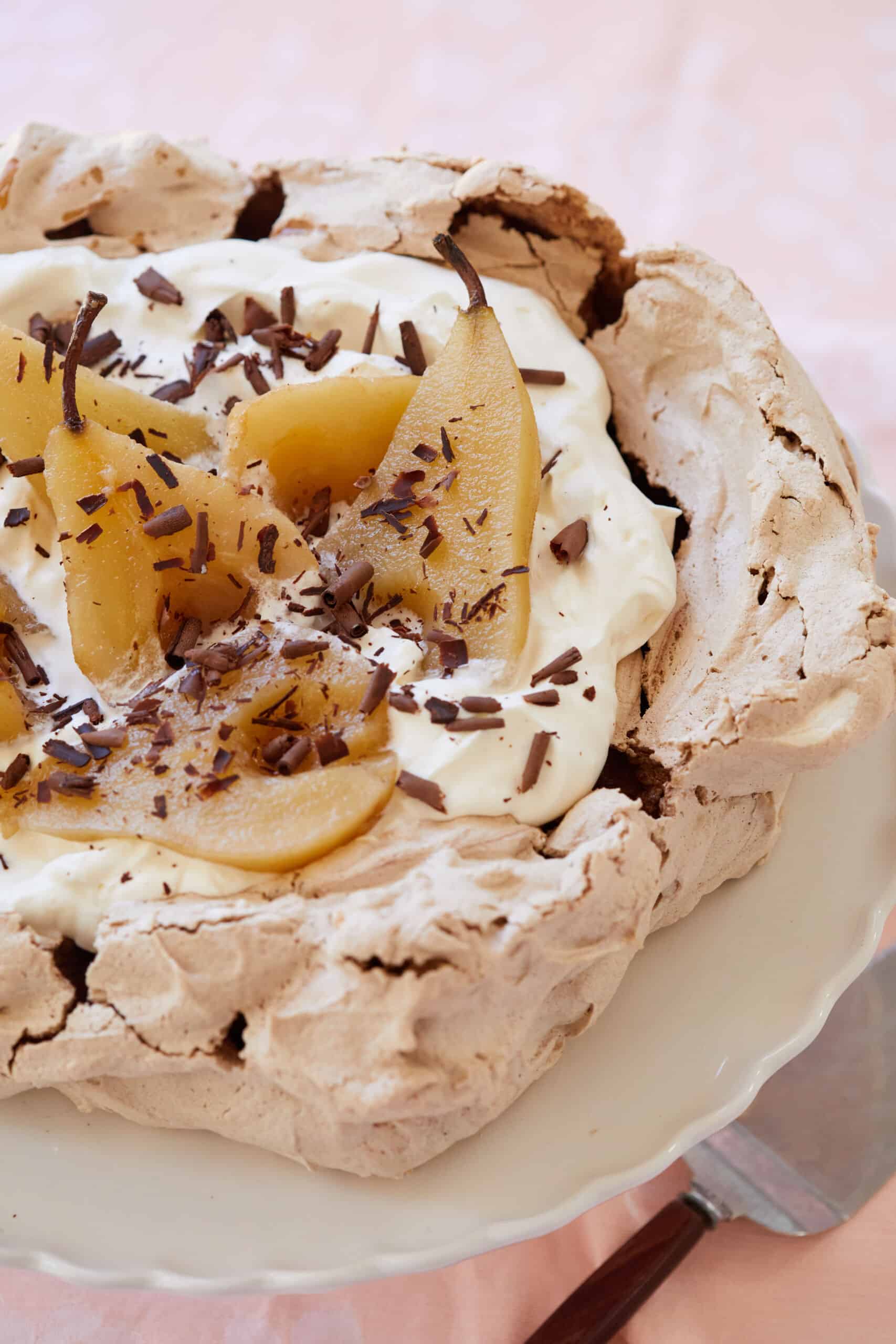 Crispy Baked Chocolate Meringue is topped with mascarpone whipped cream, then poached pears and chocolate shaves.