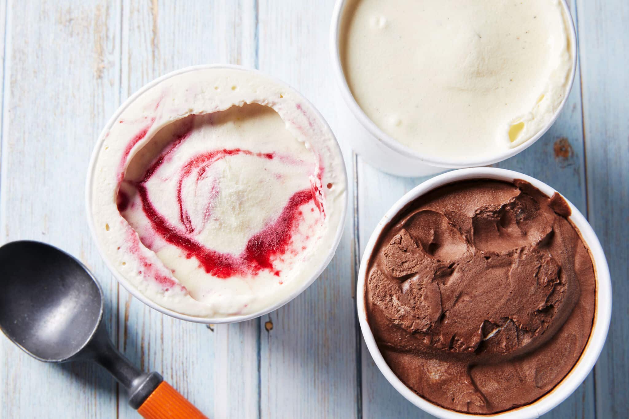 An over-head shot at 3 containers of thick, smooth No-Churn Artisanal Ice Cream in raspberry flavor, vanilla bean flavor, and chocolate flavor.