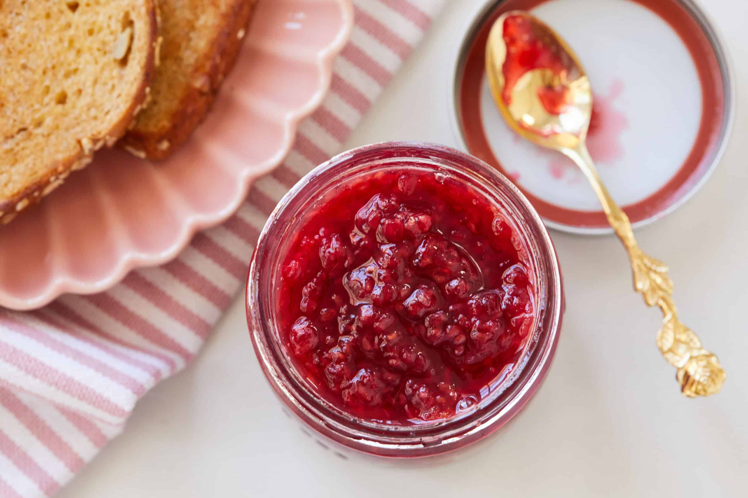 A jar of Raspberry Freezer jam is served with toast.