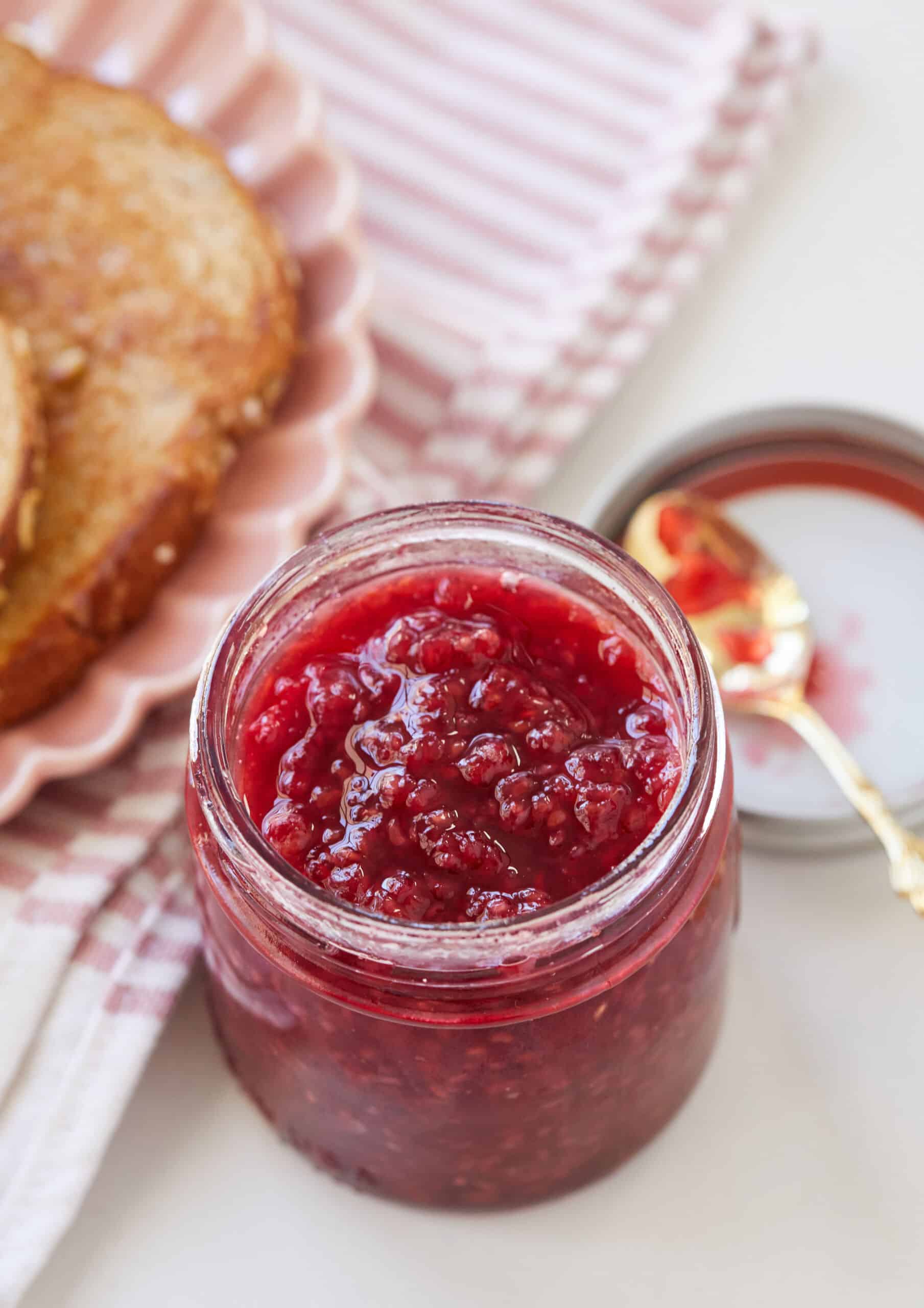 A jar of Raspberry Freezer jam is served with toast.