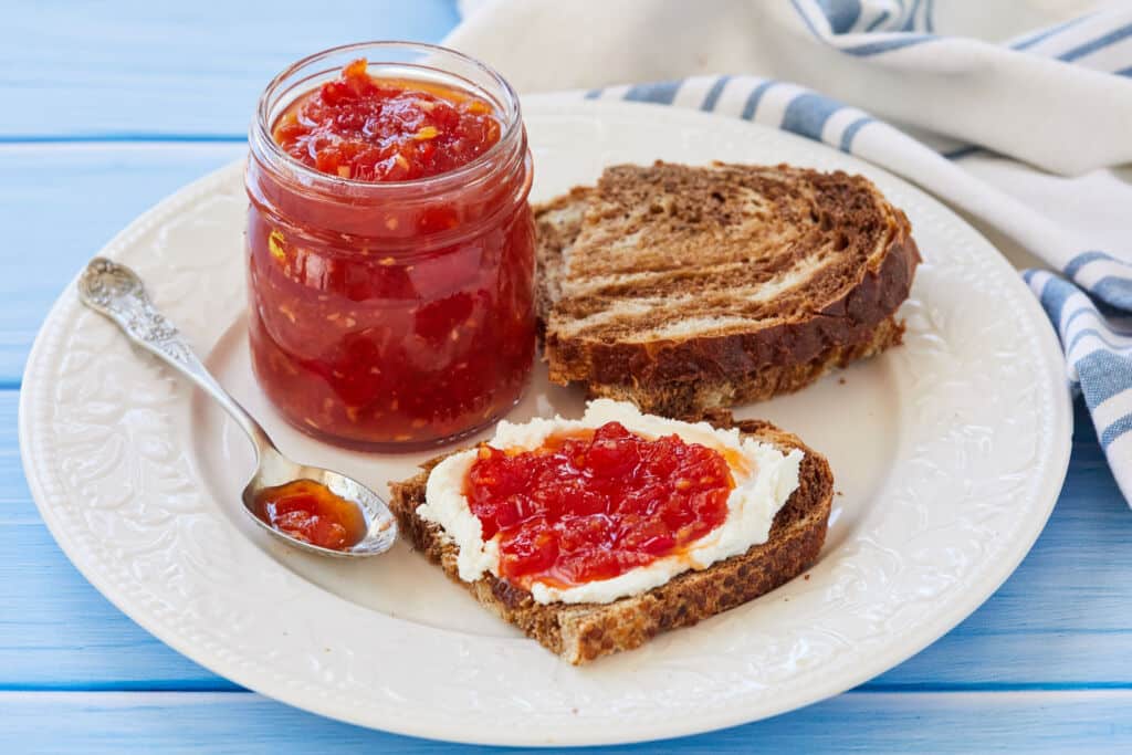Tomato Chilli Chutney is in a jar and served with toast.