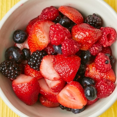 An over-head shot at a bowl of macerated fruit including strawberries, blueberries, blackberries, raspberries.