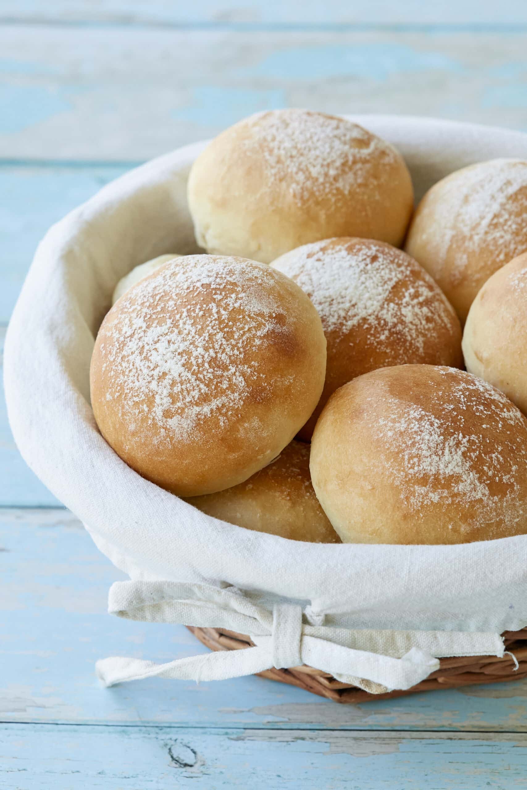 A basket of soft, fluffy Scottish Baps are lightly dusted with flour.