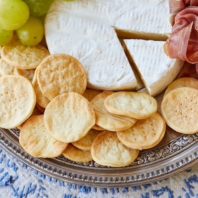 Water Crackers are paired with grapes, cheese, and salami on a charcuterie board.