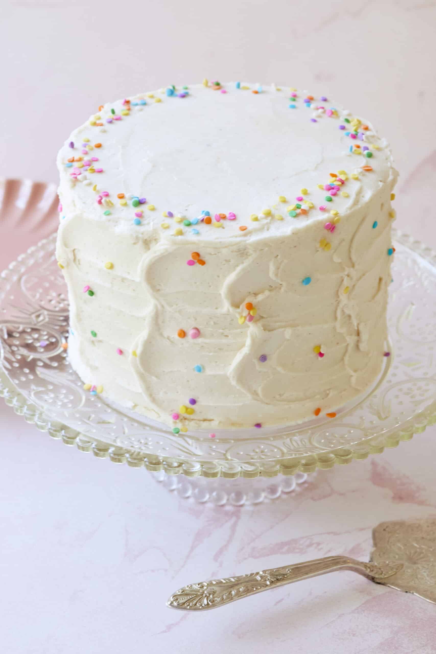 Vanilla Almond Flour Yellow Cake is frosted with white buttercream frosting and decorated with colorful sprinkles.