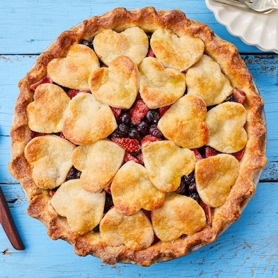 Fresh Blueberry Strawberry Pie is loaded with vibrant color blueberries and strawberries. It's baked until golden brown around the wavy edge and on the top overlapping pastry hearts.