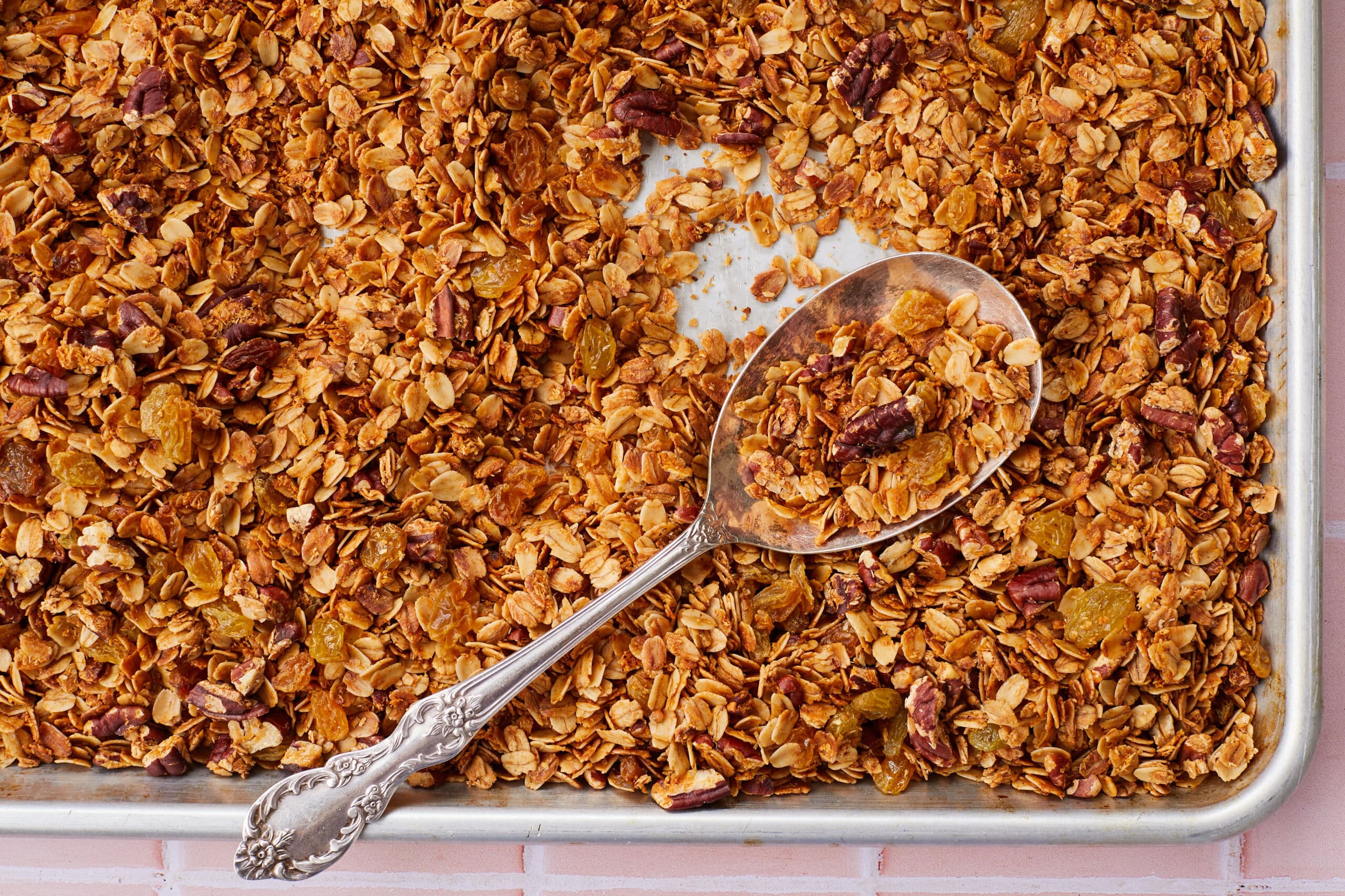 A tray of Healthy Granola (No refined sugar, baked golden brown all over, packed with oats, nuts, and raisins.