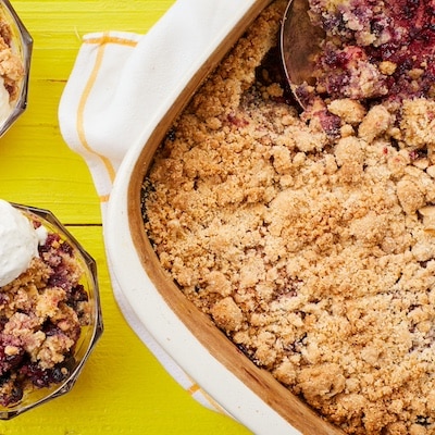 Mixed Berry Cobbler with Cake Mix is served in dessert bowls with ice cream on top. The rest of the cobbler is in the baking dish with golden crumbly soft topping and bubbly fruit filling.