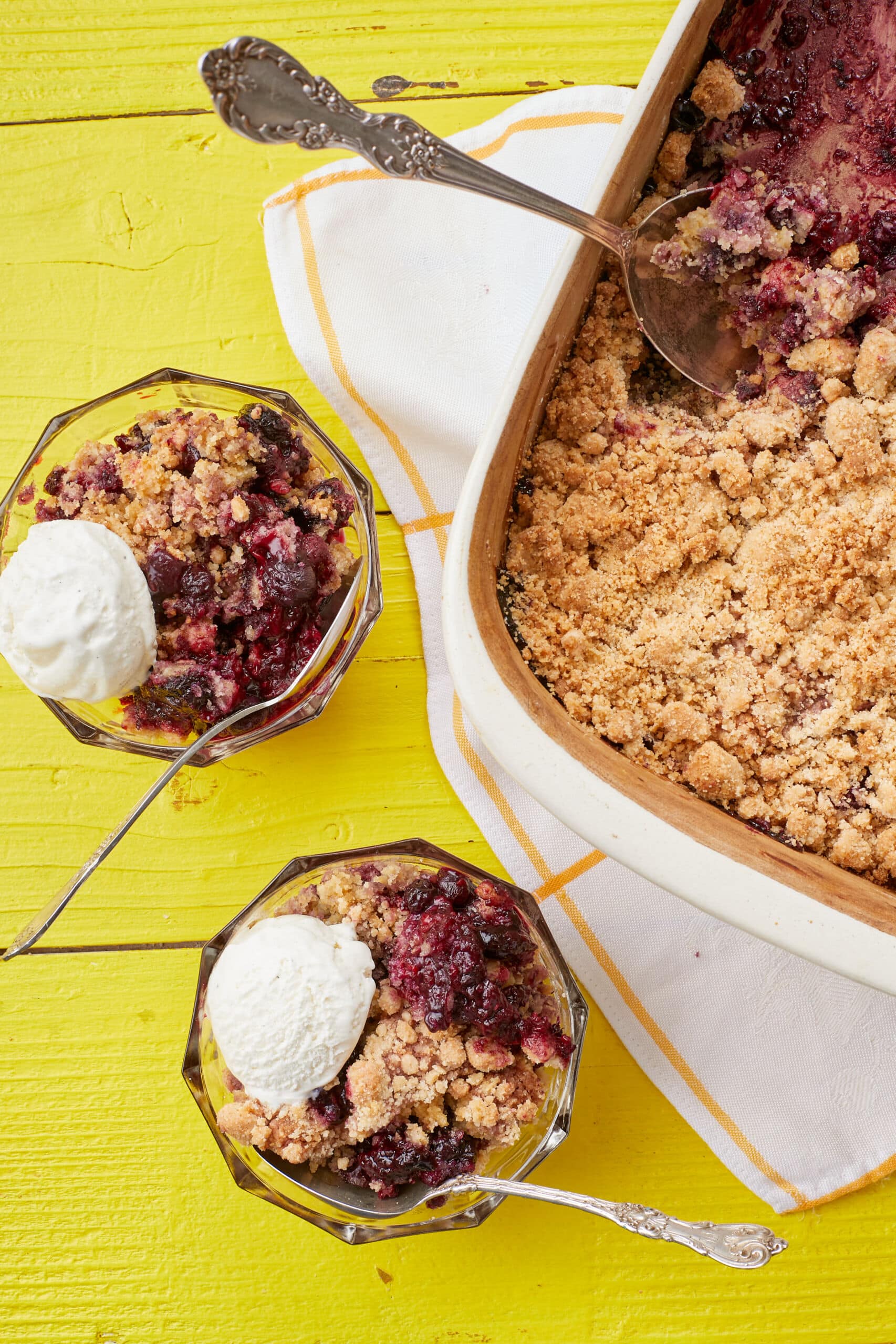 Mixed Berry Cobbler With Cake Mix was baked in a big dish and served in two glass dessert bowls, with soft berries, golden buttery cobbler topping, and scoops of ice cream .