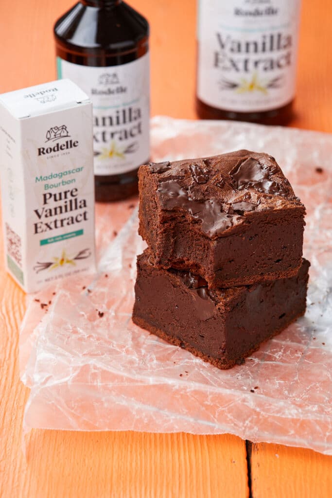 A stack of two squares of 100-Hour Brownies with Rodelle vanilla extract behind