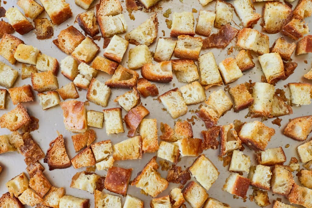 Homemade croutons on the baking tray are golden and crispy, tossed with seasoning.